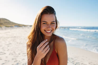 Close up portrait of beautiful young woman on the beach. Young caucasian female model in bikini on the seashore looking at camera and smiling. - JLPPF00179