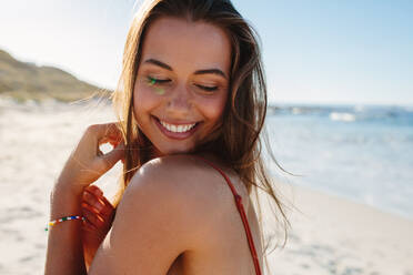 Close up Porträt der lächelnden jungen Frau am Strand. Glückliche kaukasische weibliche Modell posiert am Meer. - JLPPF00185