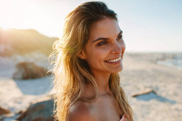 Close up Porträt einer glücklichen jungen Frau am Strand, die wegschaut. Schönes kaukasisches weibliches Modell am Meeresufer. - JLPPF00225