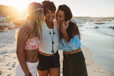 Eine Gruppe schöner junger Frauen, die zusammen am Strand spazieren gehen. Drei Freundinnen, die am Strand spazieren gehen und lächeln und den Urlaub genießen. - JLPPF00232