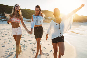 Gruppe schöner junger Frauen, die am Strand spazieren gehen. Drei Freundinnen, die am Strand spazieren gehen und sich an einem Sommertag vergnügen. - JLPPF00236