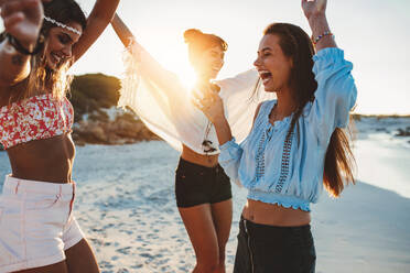 Eine Gruppe schöner junger Frauen feiert am Strand. Drei Freundinnen tanzen am Strand und genießen einen Sommertag. - JLPPF00242