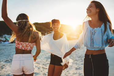 Porträt von drei jungen Freundinnen, die am Strand tanzen und lachen. Junge Frauen, die am Strand feiern. - JLPPF00243