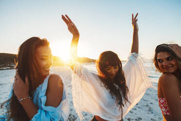 Three young woman having fun on beach during sunset. Female friends dancing on the sea shore. - JLPPF00249