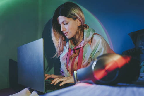 Woman using laptop sitting in bedroom at home - SVCF00173