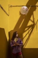 Woman wearing jacket standing in front of yellow wall - VPIF07410