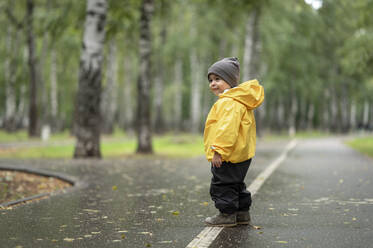 Kleiner Junge mit gelber Regenjacke auf der Straße - ANAF00027