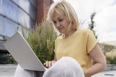 Reife blonde Geschäftsfrau mit Laptop - TOF00115