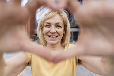 Happy woman making heart shape with hands - TOF00126