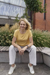 Lächelnde reife Frau mit geschlossenen Augen auf einer Bank sitzend - TOF00133