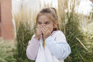 Happy girl covering mouth with hands in park - TOF00135