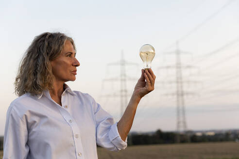 Thoughtful senior woman looking at light bulb - FLLF00740