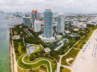 Erstaunliche Drohne Blick auf moderne Wolkenkratzer und Gebäude mit Schwimmbädern in der Nähe von sandigen Küste des wellenförmigen Ozean am sonnigen Tag in Miami Beach gelegen - ADSF38647