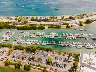 Drone Blick auf moderne Boote im Hafen inmitten Parkplatz und Sandstrand von plätschernden Ozean an einem sonnigen Tag in Miami Beach vertäut - ADSF38651