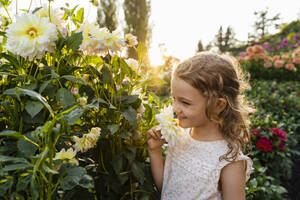 Kleines Mädchen riecht an Blumen im Garten - DIGF18837