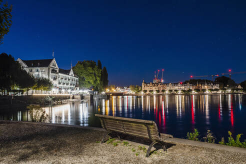 Deutschland, Baden-Württemberg, Konstanz, Bodenseeufer bei Nacht mit Stadtbeleuchtung im Hintergrund - DIGF18842