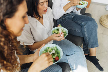 Gemischtrassige Mitbewohner essen zu Hause Salat zu Mittag - MEUF08042