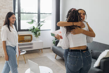 Cheerful women embracing each other in living room at home - MEUF08072