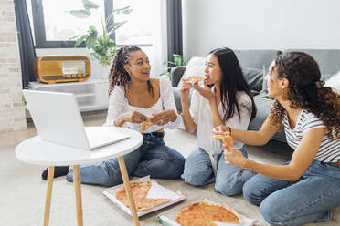 Friends eating pizza enjoying together in living room - MEUF08080