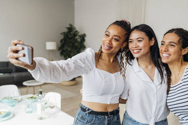 Smiling woman taking selfie with friends at home - MEUF08087