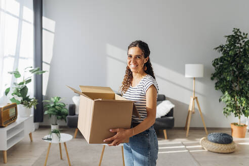 Happy woman with box relocating in new home - MEUF08097