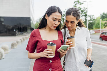 Woman sharing smart phone with friend - MEUF08109