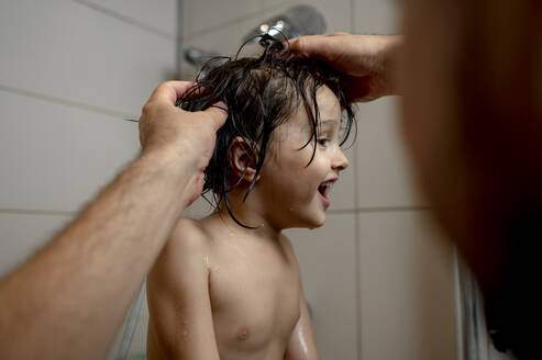 Hände des Vaters beim Waschen der Haare des Sohnes im Badezimmer - ANAF00050