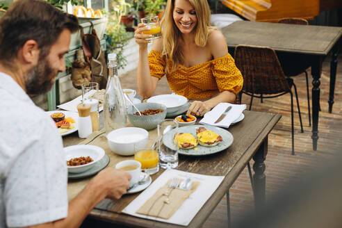 Ein Ehepaar genießt ein leckeres Frühstück in einem Hotel. Ein glückliches Ehepaar lächelt fröhlich beim gemeinsamen Essen am Esstisch. Ein Paar mittleren Alters genießt einen romantischen Urlaub in einem Ferienort. - JLPPF00352