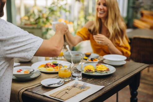Ein glückliches Paar mittleren Alters, das beim gemeinsamen Frühstück in einem Luxushotel mit Teetassen anstößt. Ein Ehepaar, das einen romantischen Wochenendausflug genießt. - JLPPF00362