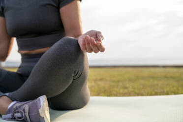 Frau sitzt auf Übungsmatte und macht Yoga - VPIF07420