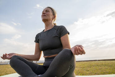 Mature woman with eyes closed meditating on grass - VPIF07421