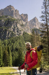 Wanderer mit Rucksack und Wanderstöcken vor den Dolomiten, Italien - JCCMF07330