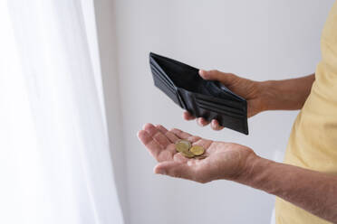 Hands of man holding wallet and coins at home - SVKF00538