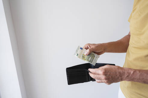 Hände eines Mannes, der eine Brieftasche mit einer Banknote hält, stehen an einer Wand zu Hause - SVKF00539