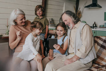 Happy grandparents with kids watching tablet PC at home - YTF00120