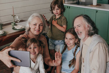 Grandmother with grandchildren taking selfie through tablet PC at home - YTF00121