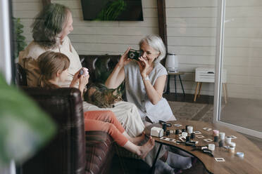 Frau fotografiert einen älteren Mann und seine Enkelin mit einer alten Filmkamera zu Hause - YTF00155