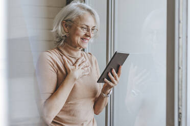 Glückliche reife Frau bei Videoanruf über Tablet-PC zu Hause - YTF00169