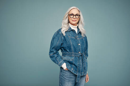 Mature woman feeling empowered in a studio. Self-confident woman looking at the camera while standing against a studio background. Grey-haired woman embracing girl power. - JLPPF00548