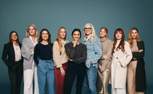 Cheerful group of women standing together in a row. Strong and empowered women looking at the camera with confidence in a studio. Group of self-assured women embracing girl power. - JLPPF00600