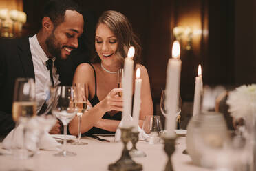 Verliebtes Paar sitzt bei einer Dinnerparty mit einem Glas Champagner zusammen. Mann und Frau genießen bei einer Gala-Dinnerparty. - JLPPF00658