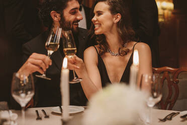 Schönes junges Paar sitzt am Esstisch mit Kerzen und trinkt Wein. Romantischer Mann und Frau bei einer Gala-Dinner-Party. - JLPPF00662