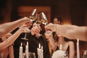 Group of men and women toasting champagne at a dinner party. Group of friends celebrating with drinks at gala night. - JLPPF00665