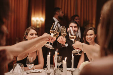 Eine Gruppe von Menschen stößt auf einer Gala-Party mit Getränken an. Freunde genießen eine Silvesterparty mit Getränken. - JLPPF00666