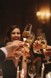 Eine Gruppe von Männern und Frauen genießt eine Dinnerparty und stößt mit Champagnergläsern an. Eine Gruppe von Freunden trinkt bei einer Galanacht. - JLPPF00736