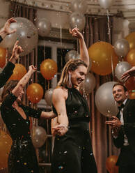 Schöne junge Frau tanzt auf einer Galanacht mit Freunden. Eine Gruppe von Freunden hat eine tolle Zeit beim Tanzen auf einer Party. - JLPPF00747