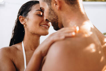Junges, romantisches Paar unter einer Dusche im Freien. Ein junges, kokettes Paar duscht zusammen im Freien in einem Luxus-Spa-Resort. Ein liebevolles Paar, das sich in den Flitterwochen kennenlernt. - JLPPF00873