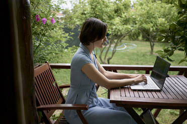 Freelancer working on laptop sitting on balcony - ANNF00001