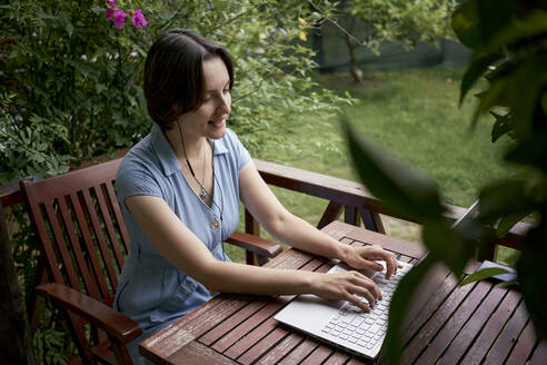 Freelancer talking on video call using laptop sitting on balcony - ANNF00002