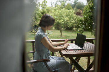 Freiberufler mit Laptop auf dem Balkon sitzend - ANNF00003